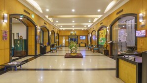 A hotel lobby with a reception desk, seating area, and a large vase with flowers.
