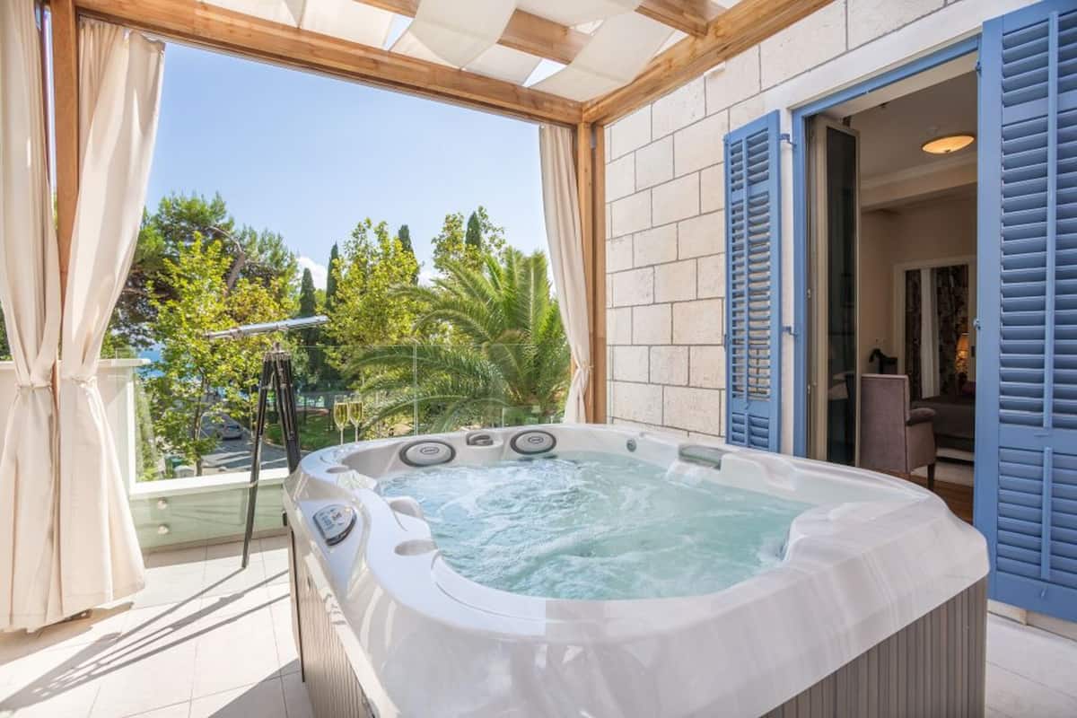 A hot tub on a balcony with a view of trees and a building.