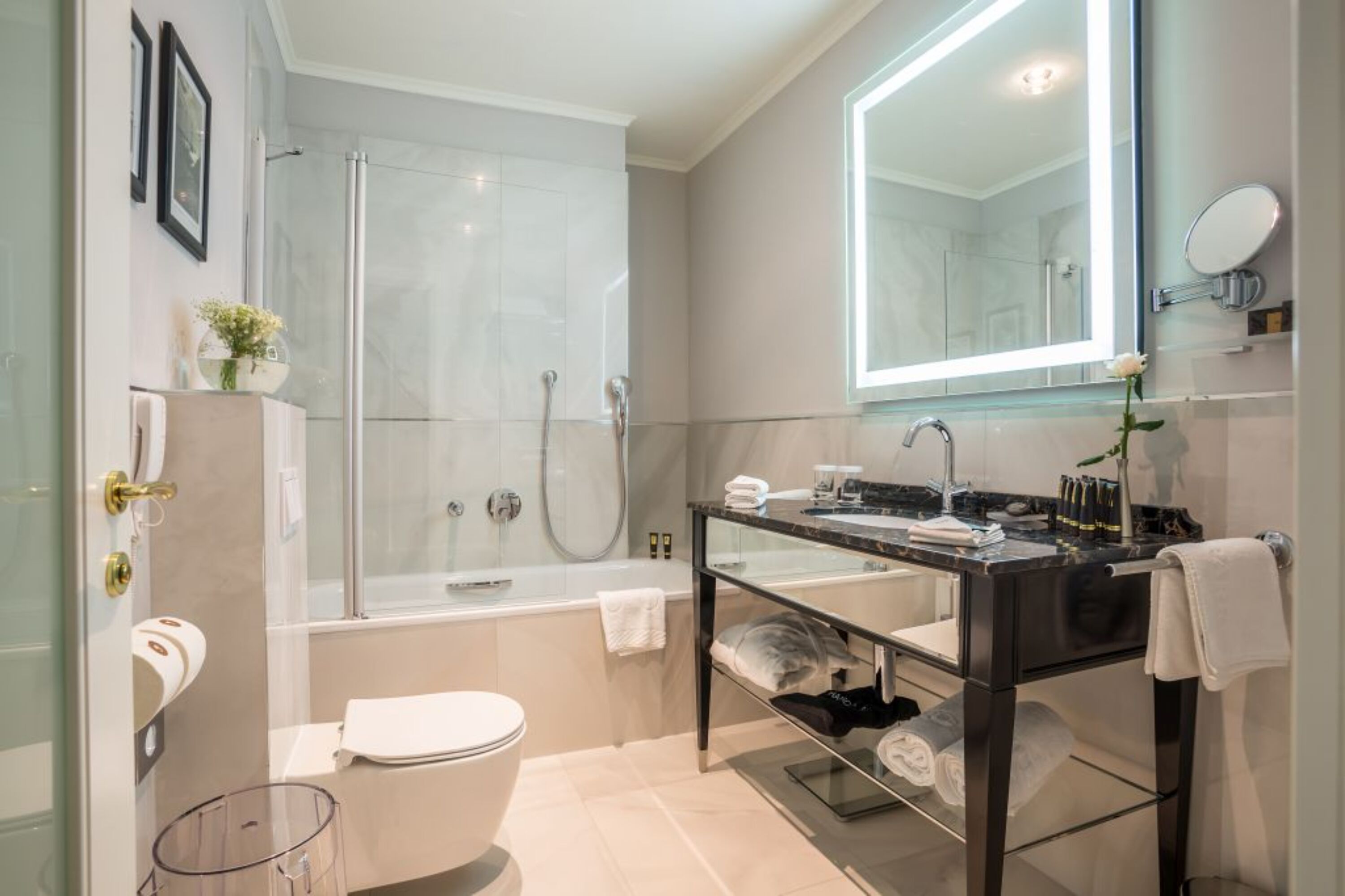 Un baño moderno con cabina de ducha de vidrio, un tocador negro con espejo y un inodoro.