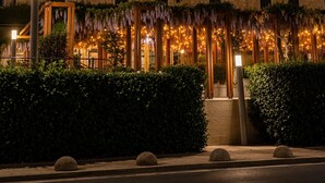 A multi-story hotel with a stone facade, illuminated signage, and a decorative entrance with hanging plants. - Hotel Park (Split)