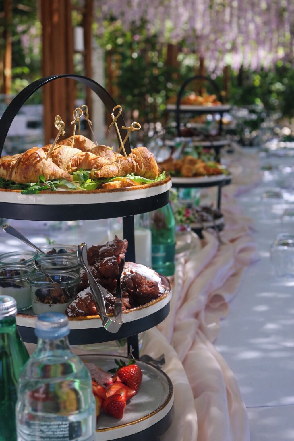 A buffet setup with croissants, desserts, and fruit.