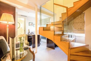 Ein modernes Interieur mit einer Holztreppe, einem runden Tisch mit Lampe und einer Vase mit Blumen.
