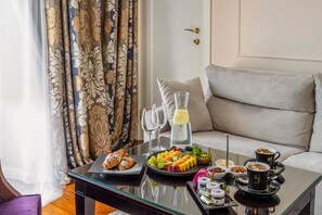 A breakfast setup on a glass table with croissants, fruit, and coffee cups.