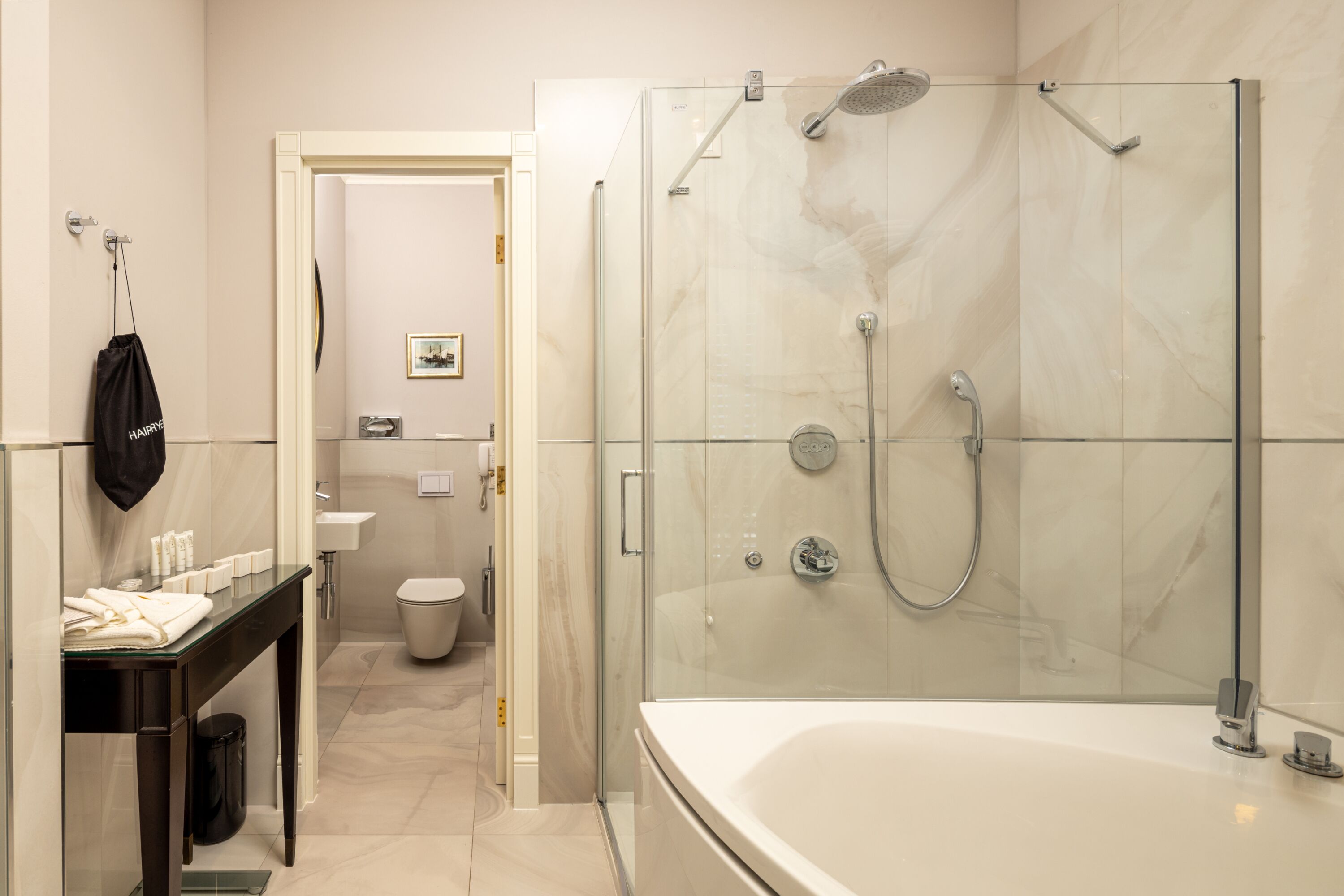 Un baño moderno con ducha envuelta en vidrio, un inodoro separado y un tocador con espejo.