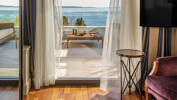 A room with a view of the sea, a sofa, a table, and a TV. - Hotel Park (Split)