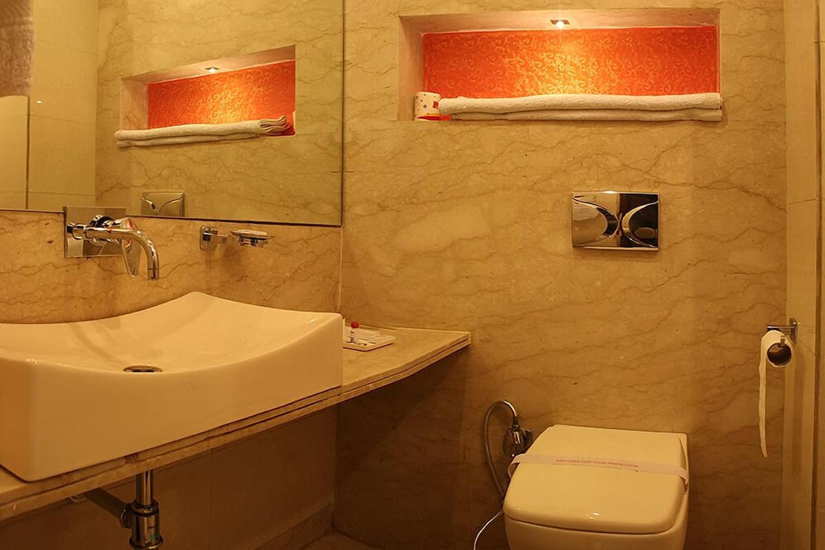 A bathroom with a large sink, a mirror, a toilet, and towel racks.