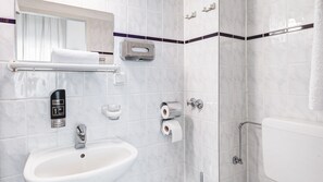 Ein modernes Badezimmer mit Waschbecken, Spiegel, Handwaschbecken, Toilettenpapier und einer Duschkabine.