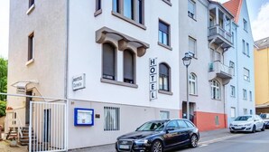 Un bâtiment d’hôtel moderne, avec une façade blanche, de nombreux balcons et une enseigne indiquant qu’il s’agit d’un hôtel.