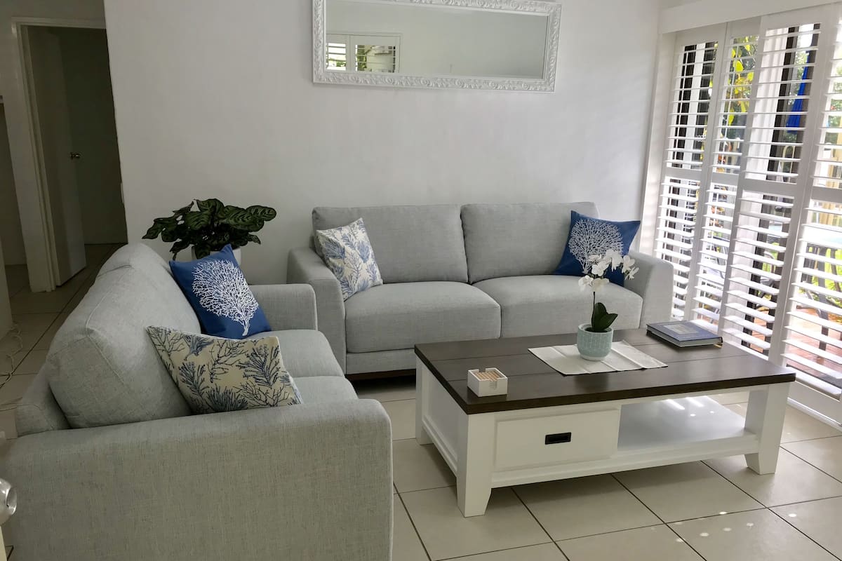 A living room with two grey sofas, a coffee table, and a potted plant.