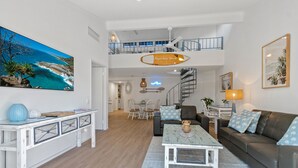 Un vaste espace de vie doté d’un haut plafond, un coin repas et un escalier menant à l’étage supérieur.