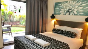 Une chambre d’hôtel avec un lit, un coin repas et une vue sur le jardin.