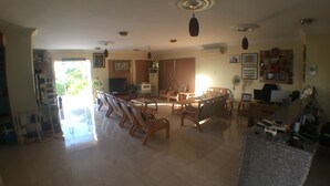 A spacious living room with a dining area, a television, and a ceiling fan.