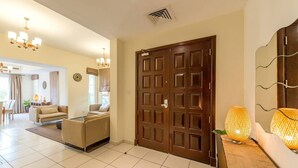 A modern living room with a sofa, a dining area, and a large wooden door. - Medlock Villas (Dubai)