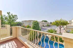 Un balcon avec une piscine, donnant sur un quartier résidentiel avec des maisons et de la verdure.