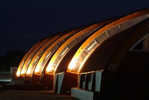 A modern building with a curved roof structure and illuminated interior panels. - Pago Del Vicario (Ciudad Real)