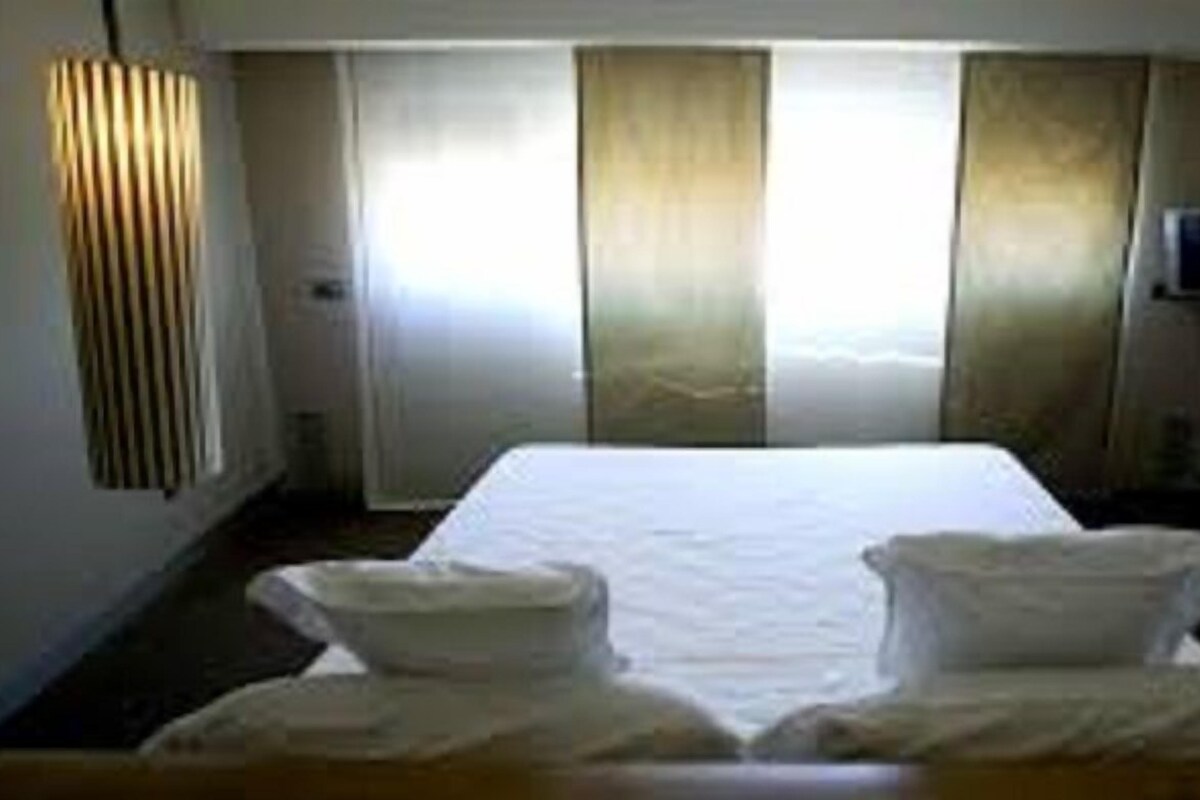 A hotel room with a large bed, two bedside tables, and curtains.