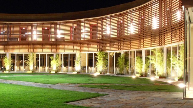 Um edifício moderno com fachada curva, grandes janelas de vidro e um gramado bem cuidado.