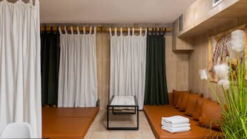 A modern spa room with a seating area, a table, and a large window with curtains.
