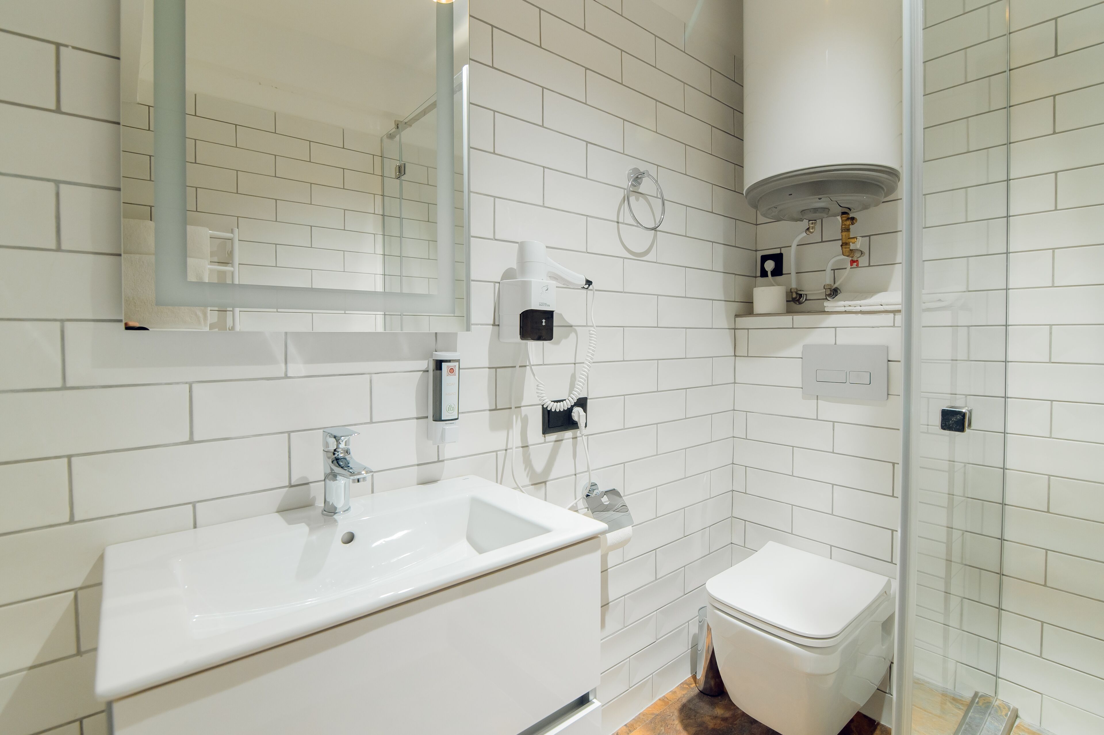 Un baño moderno con lavamanos, inodoro y zona de ducha blancos.