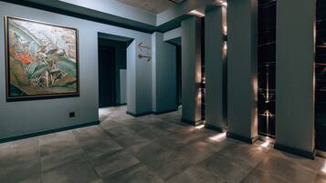 Un pasillo con una gran pintura botánica, flechas direccionales e iluminación moderna.