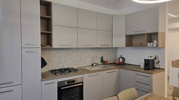 A modern kitchen with white cabinets, a gas stove, an oven, and a dining area with a table and chairs.