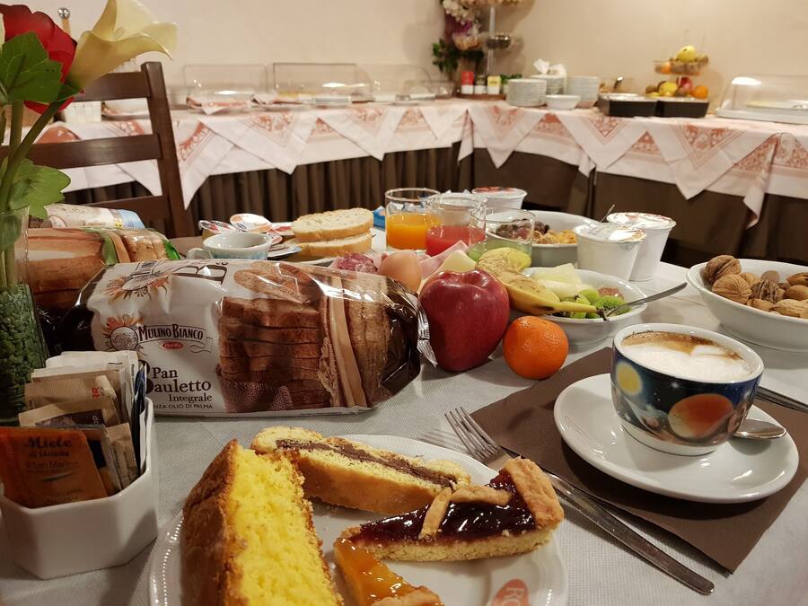 A breakfast buffet with various food items, including bread, pastries, fruits, and beverages.