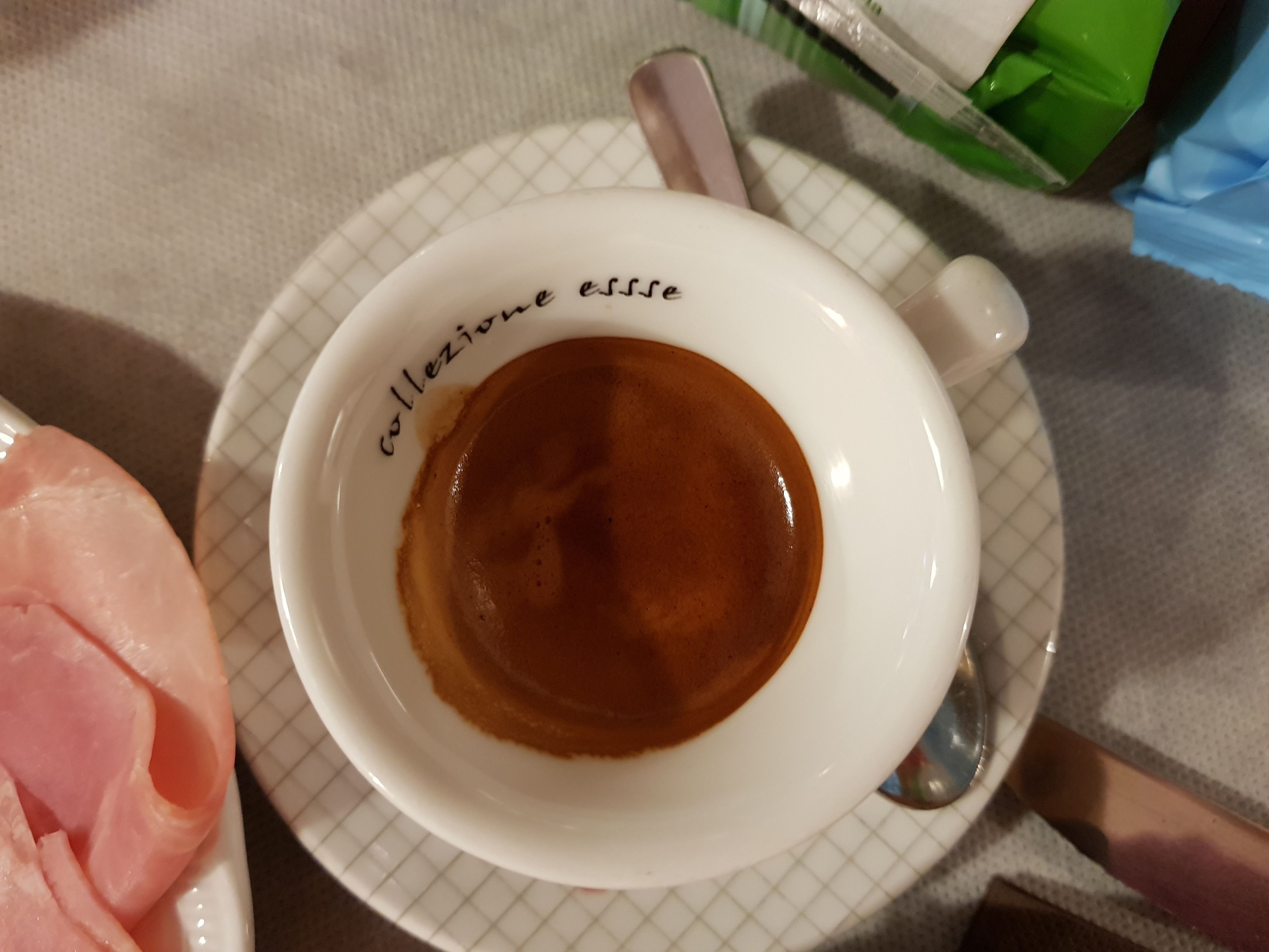 Una taza de café sobre un plato blanco con diseño de cuadrícula.