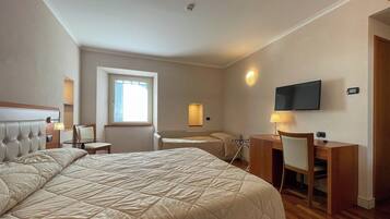 Una habitación de hotel con una cama grande, un escritorio, una silla, un televisor y una ventana.