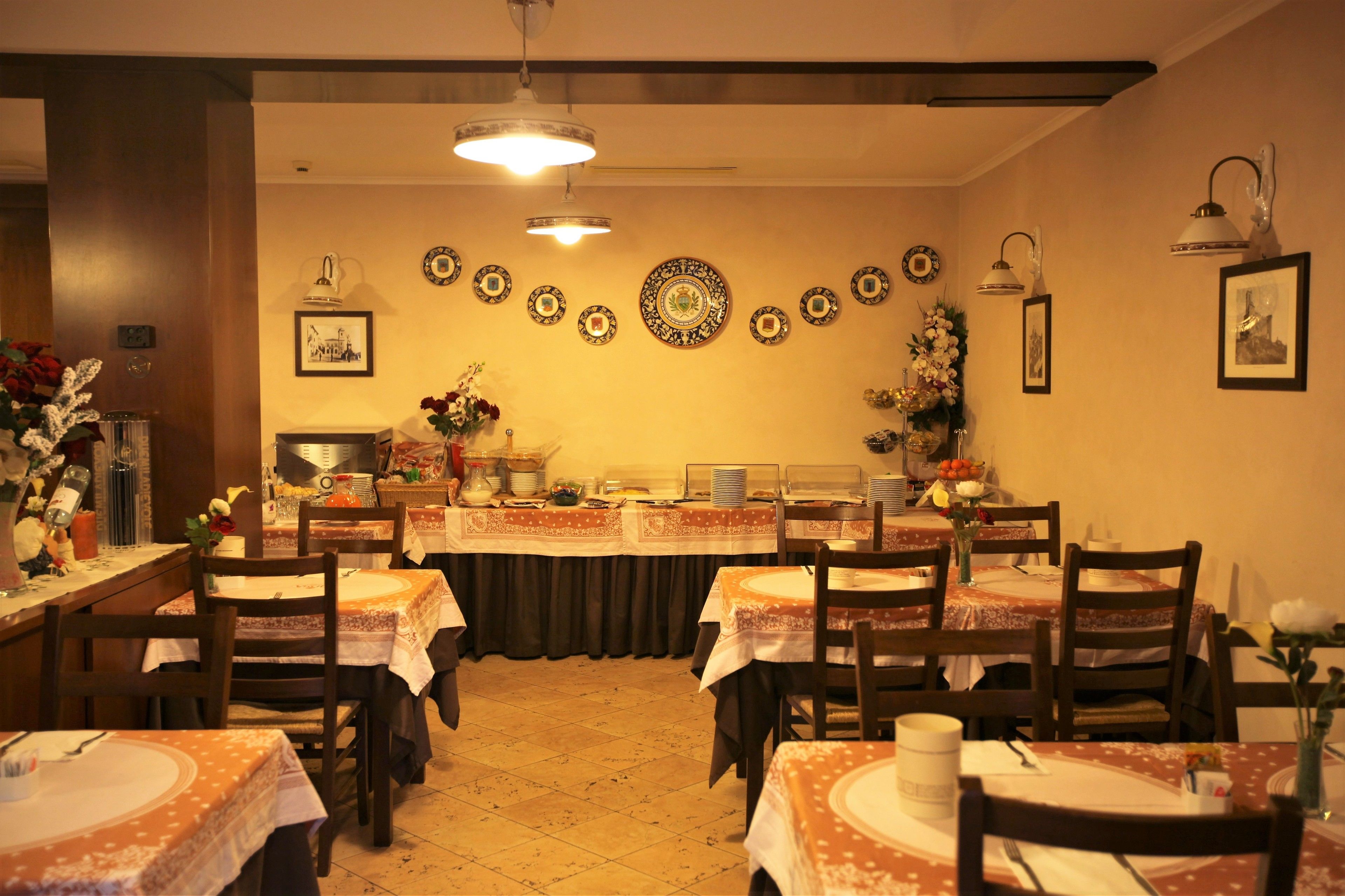 Un comedor con varias mesas y sillas, una barra libre central y platos decorativos en la pared.
