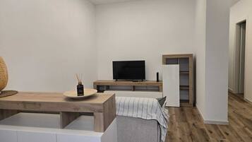 A modern, minimalistic living space with a flat-screen TV, a wooden coffee table, and a built-in bench.