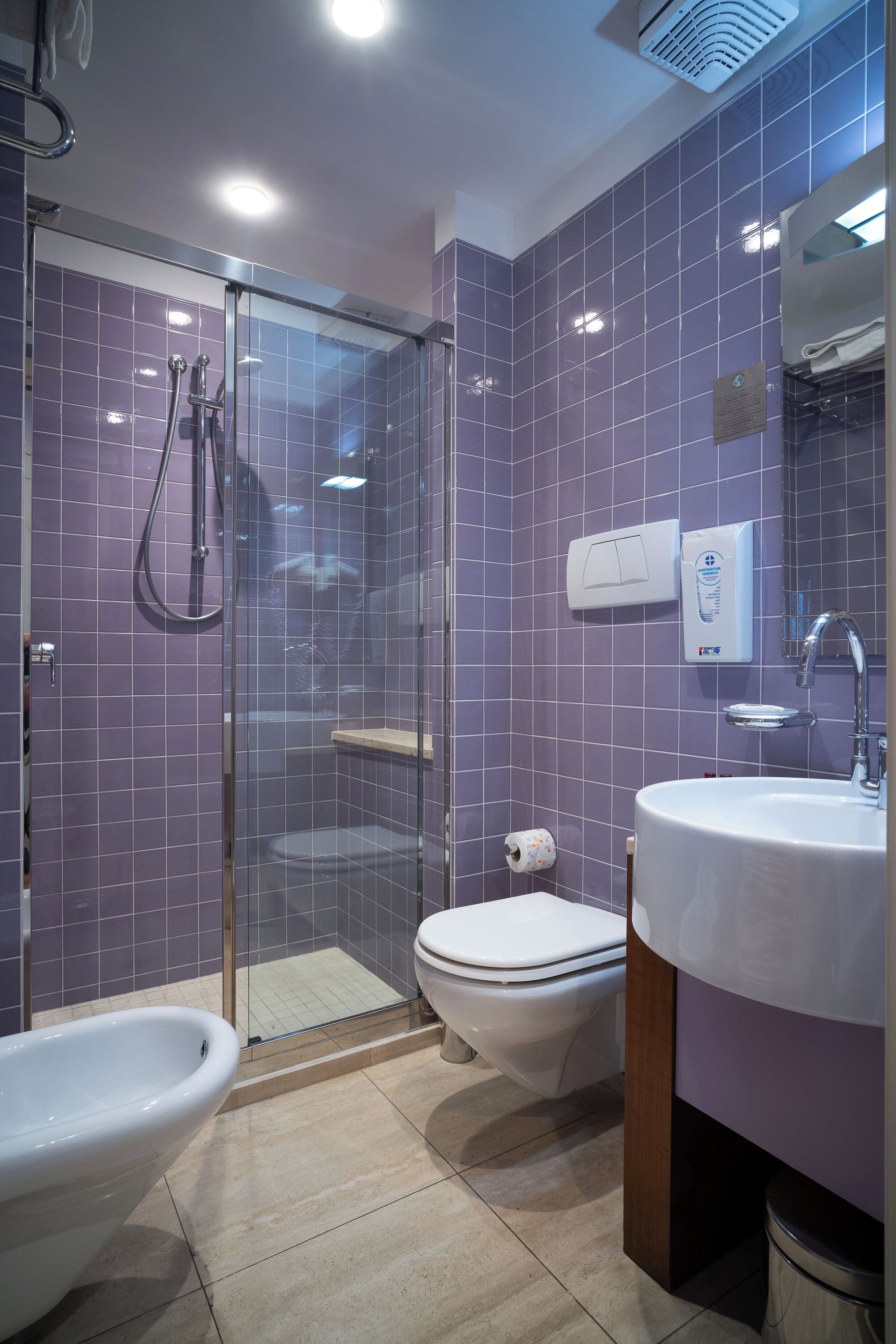 Une salle de bain comprenant une douche à parois de verre, des toilettes, un bidet et un lavabo.