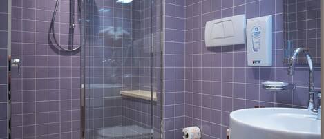 Une salle de bain comprenant une douche à parois de verre, des toilettes, un bidet et un lavabo.