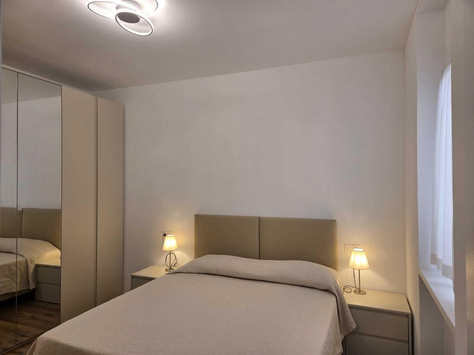 A bedroom with a bed, bedside tables, and a mirror.