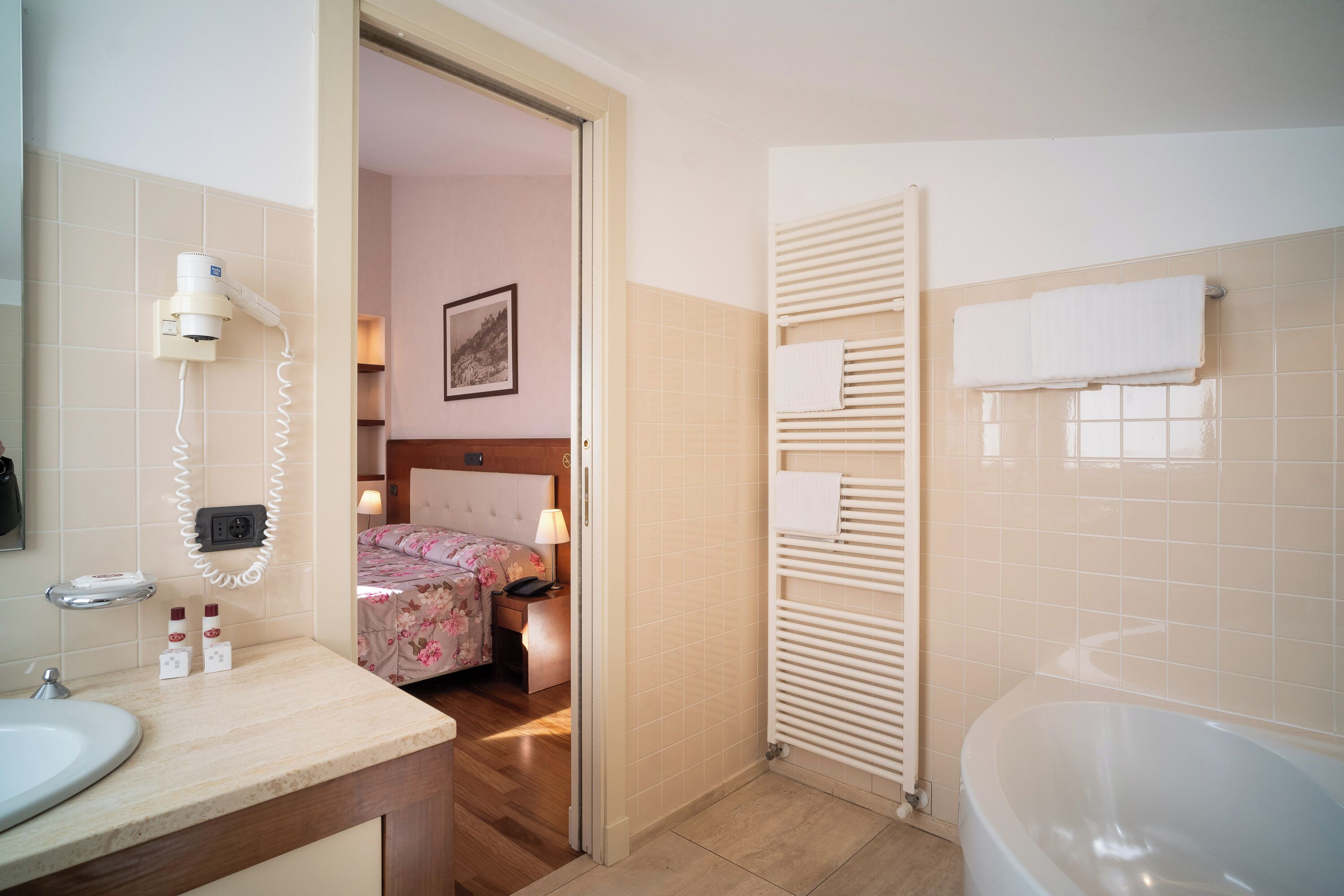 A hotel bathroom with a bathtub, a sink, and a shower area.