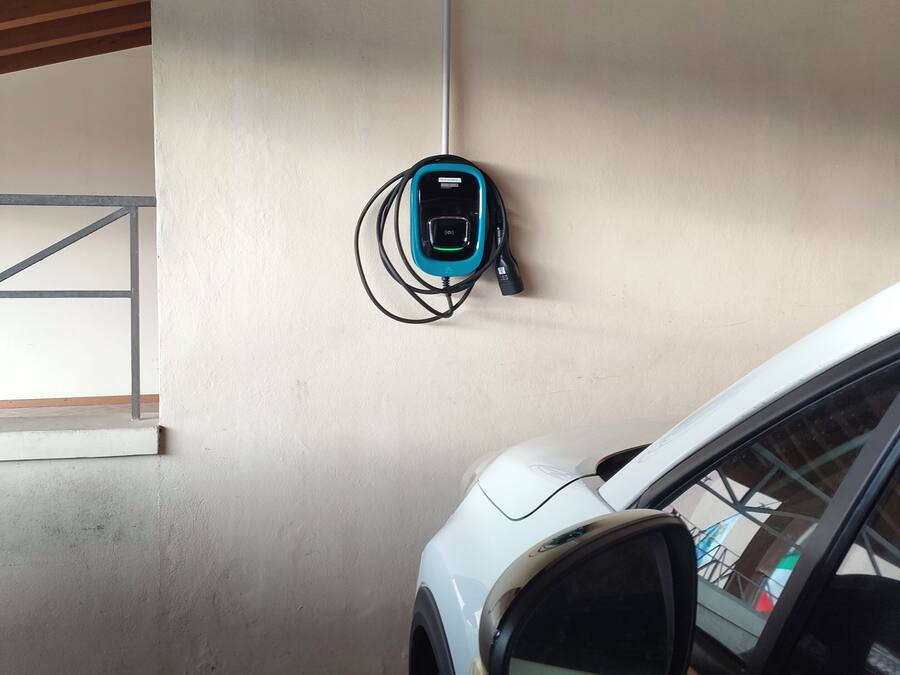 Un'auto bianca parcheggiata all'interno con una stazione di ricarica elettrica montata a parete.