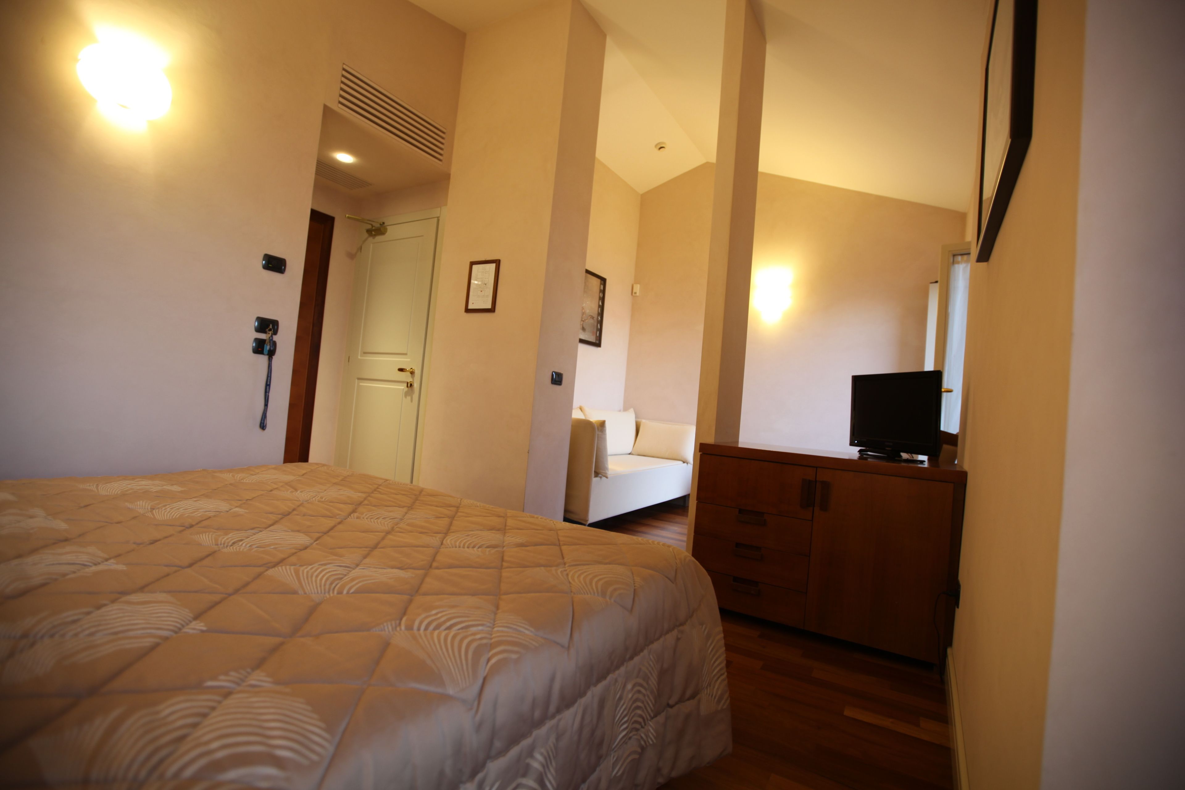 Un dormitorio con una cama grande, un aparador, un televisor y una puerta que da a otra habitación.