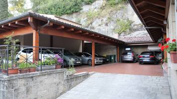 Un carport coperto con diverse auto parcheggiate, un muro in pietra e piante in vaso.