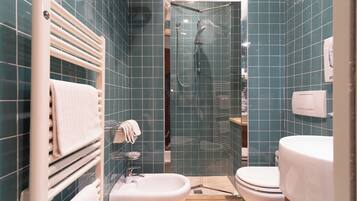 Un baño con ducha de vidrio, lavamanos blanco y un inodoro.