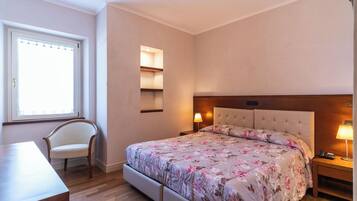 Un dormitorio con una cama grande, una silla, una mesita de noche y una ventana.
