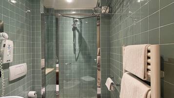 Un baño moderno con ducha de vidrio, inodoro, lavamanos y toallero.