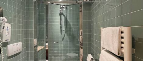 A modern bathroom with a glass-enclosed shower, a toilet, a sink, and a towel rack.