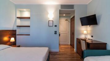 Habitación de hotel con dos camas, un escritorio, un televisor y una puerta que da a un baño.