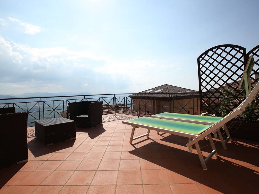 Una terrazza con tavolo e sedie, vista sul mare e una recinzione.