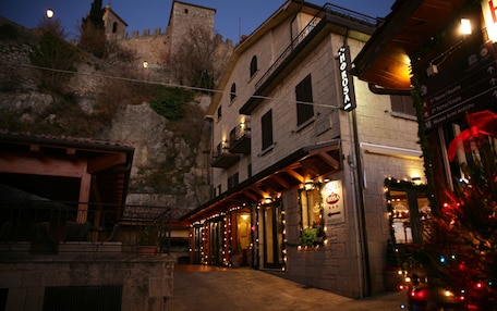 A hotel with a sign reading "Hotel Rosa" and a view of a castle in the background.