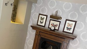 A fireplace with three framed butterfly pictures above it, set against a patterned wall.