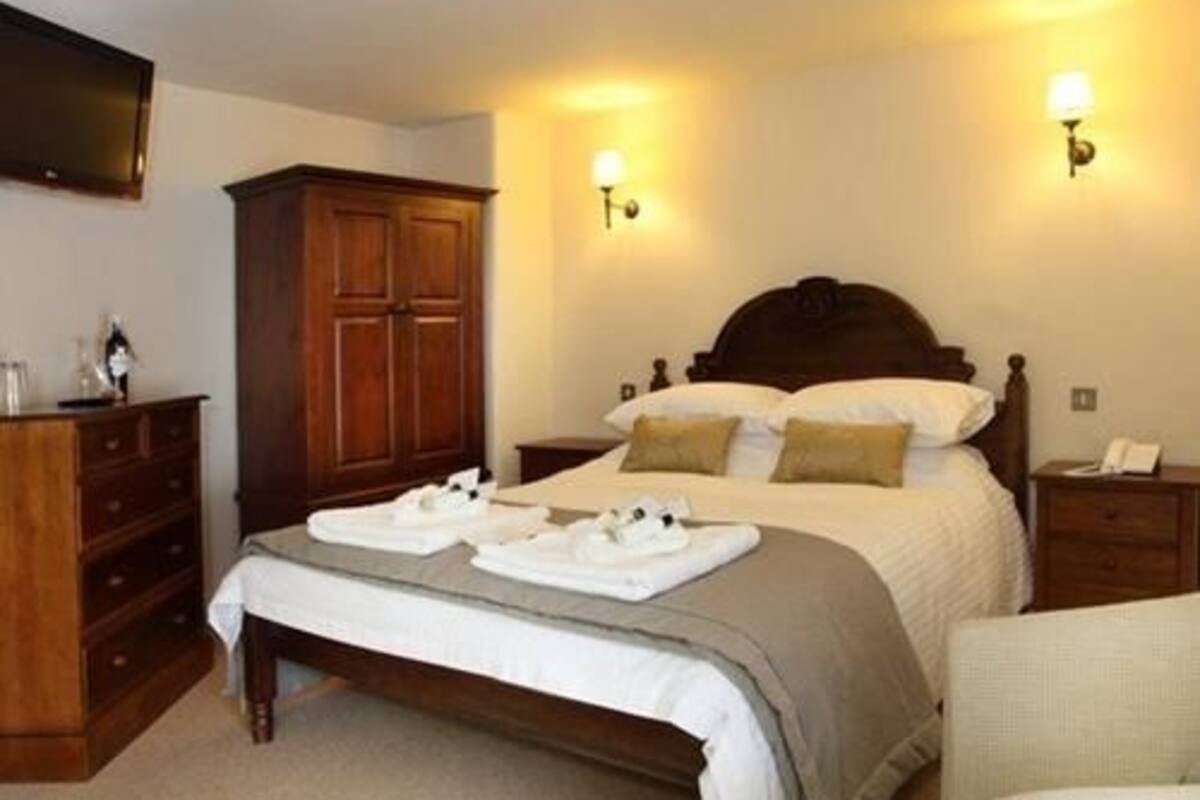 A neatly made bed with a wooden headboard, a bedside table with a lamp, and a wardrobe.