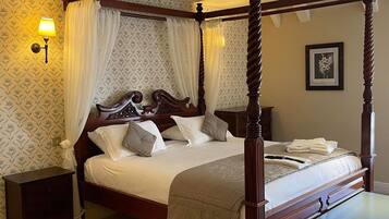 A four-poster bed with a canopy, a bedside table, a nightstand, and a bench.