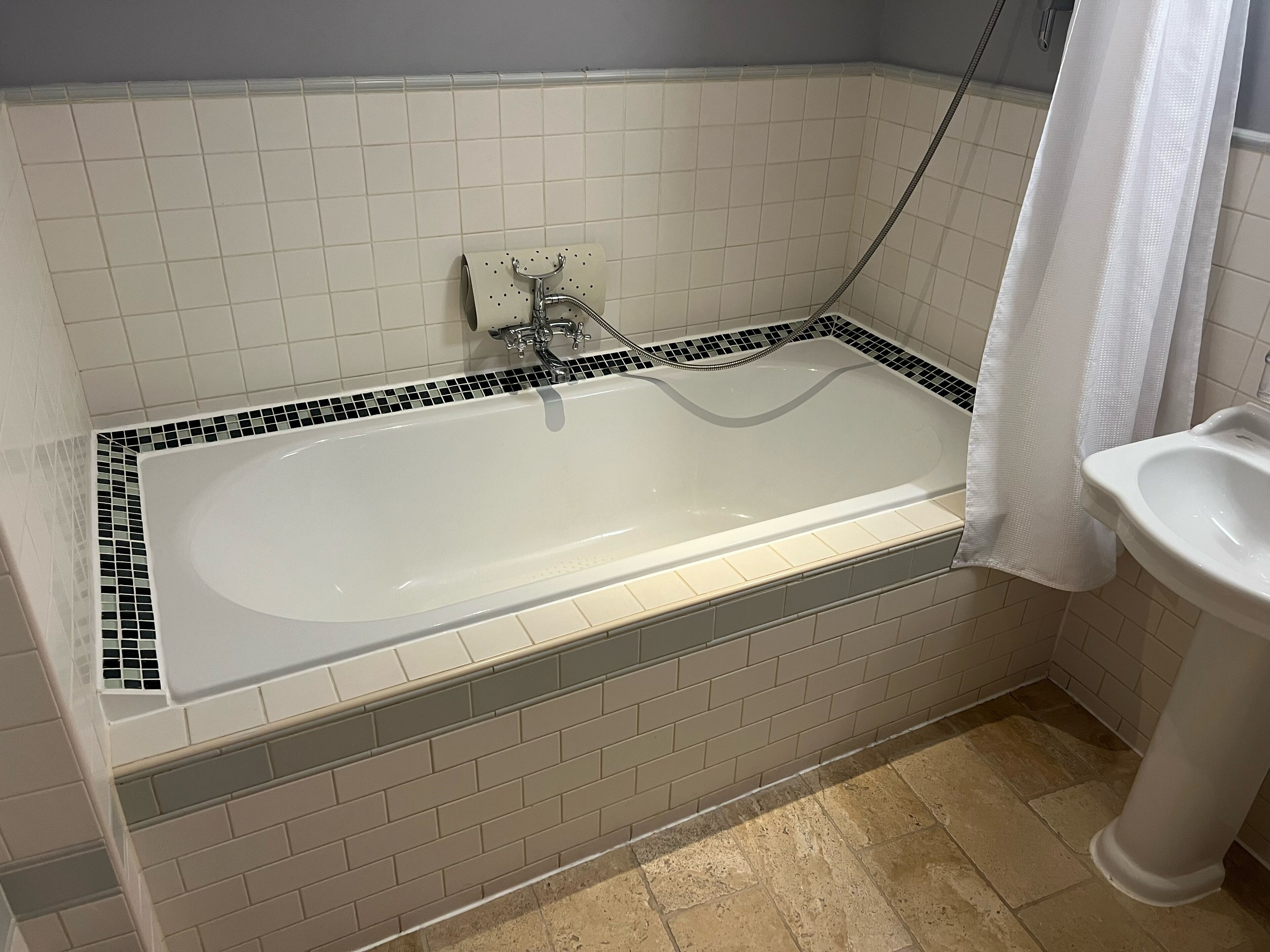 Une salle de bain avec une baignoire blanche, une douche et un lavabo.