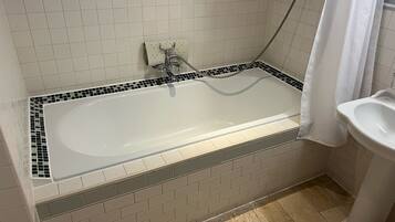 Une salle de bain avec une baignoire blanche, une douche et un lavabo.