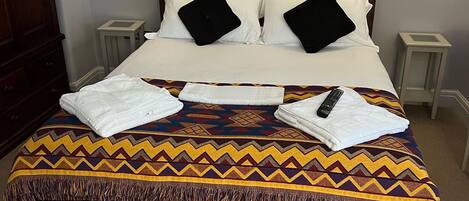 A neatly made bed with a patterned blanket, two bedside lamps, and a wooden headboard.